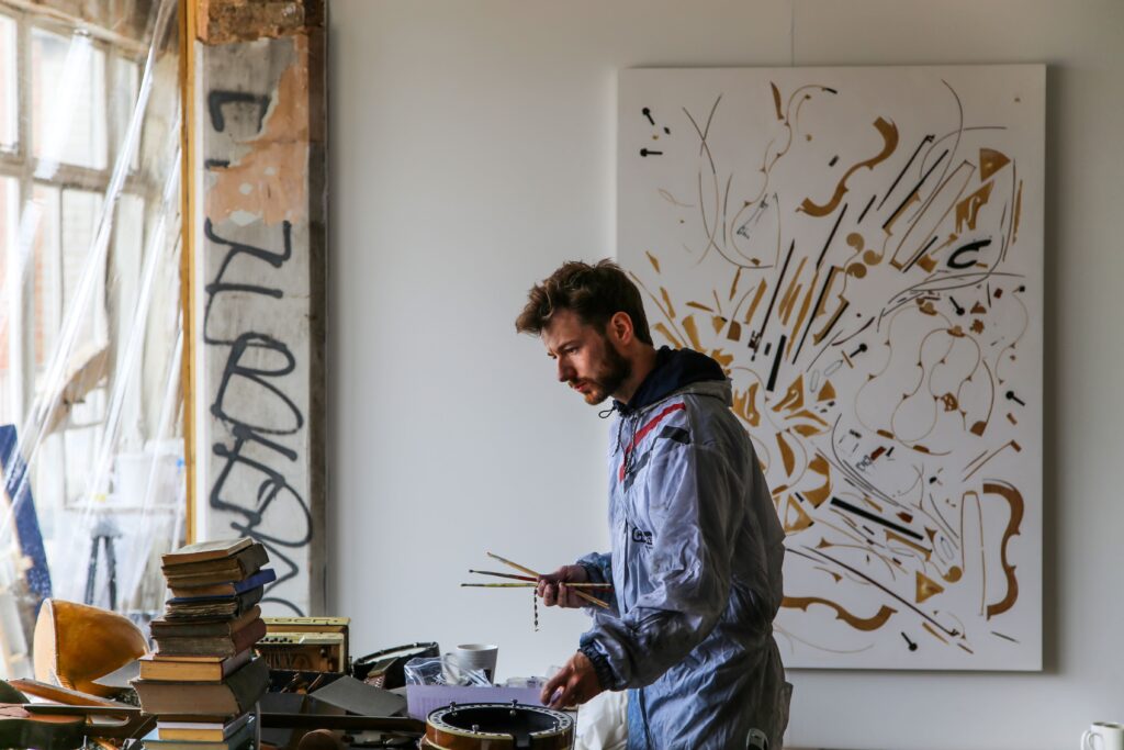 Der britische Künstler Oliver Beer bespielt Pigmente auf einer Leinwand über Lautsprecher mit Klängen und macht Kunst, die durch Sound entsteht.